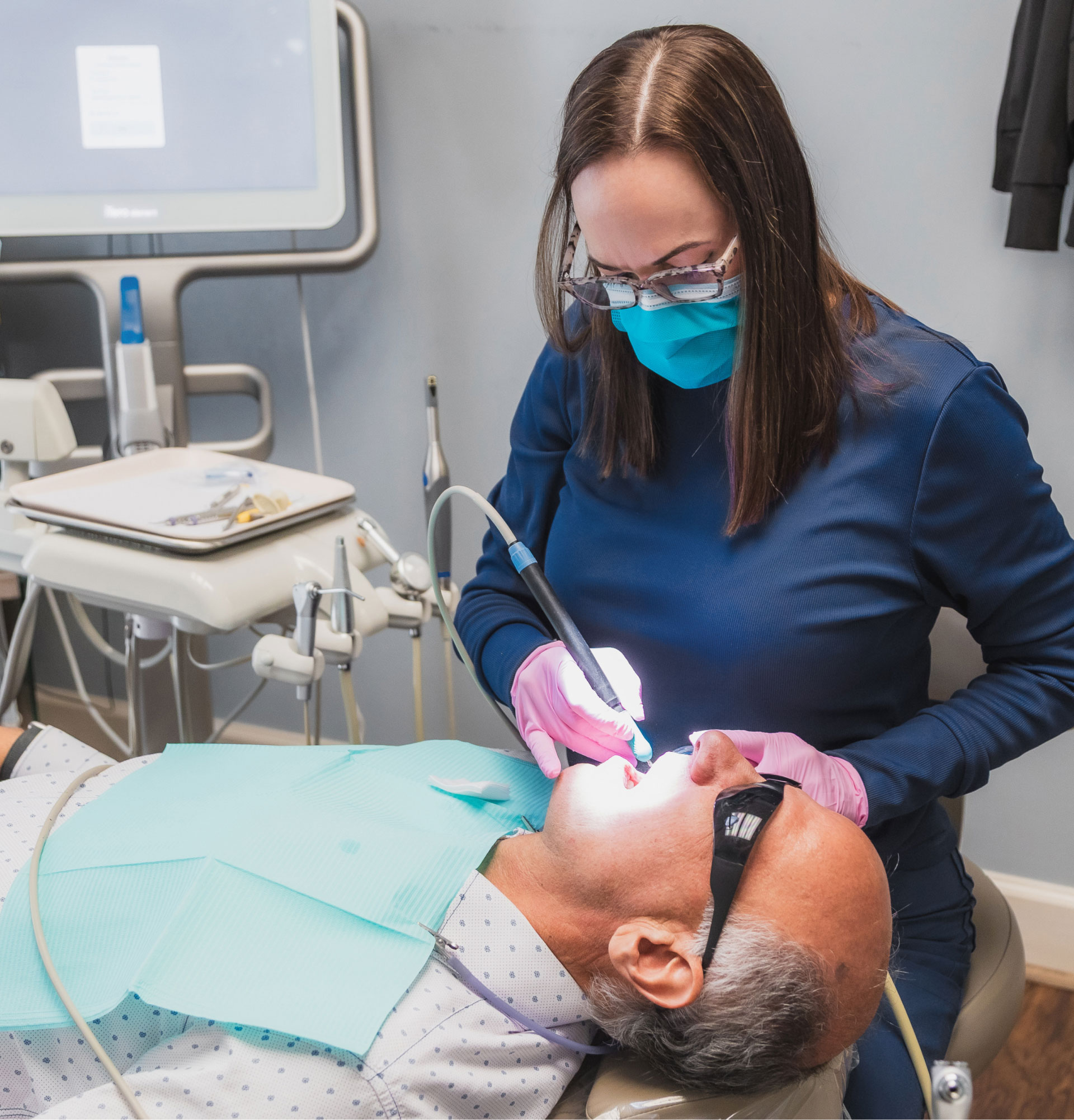 dental assistant performing dental procedure on patient in exam room