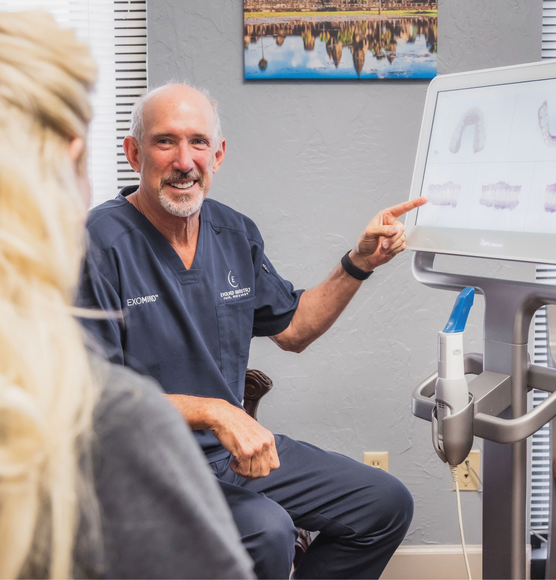 Dr. Alhadef pointing to dental scans on iTero machine screen as he explains a procedure to his patient
